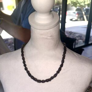 Dark Brown small bead necklace on a white body form with a window background