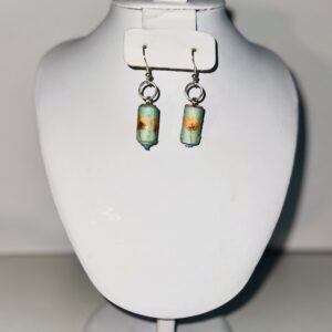 Earrings with silver fixings with cylinders that are bright blue on a neutral background