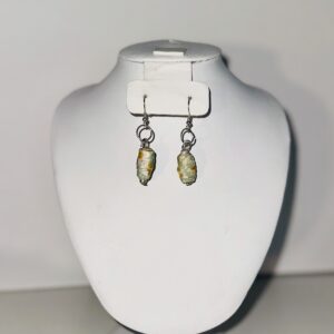 Earrings with silver fixings and beads with blue and yellow flowers on a neutral background.