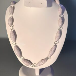Necklace of white beads with silver fixings on a white form with a dark room background