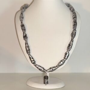 Necklace of silver and black paper beads with a coordinated artist made charm on a white form with a neutral background