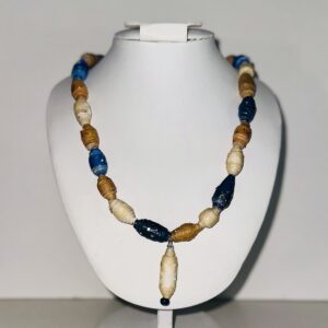 Necklace of dark blue denim, acid wash denim, light wash denim, tan, and butter yellow, with an artist made charm of a bead of butter yellow with a starburst of paler yellow on a white form with a neutral background