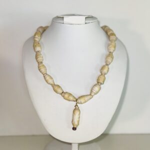 Necklace of butter yellow paper-based beads with a large butter yellow charm with a paler starburst design, on a white form with a neutral background