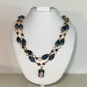 Double strand necklace of black paper beads and both matte and shiny purple beads with gold fixings.