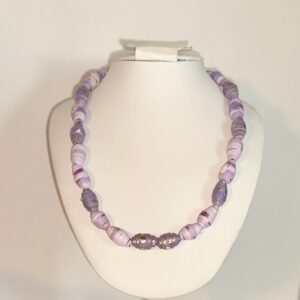 Necklace of lavenders and purples paper beads on a white form with a neutral room background