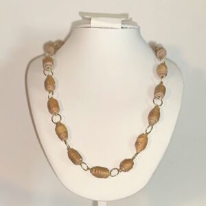 Necklace of honey brown paper beads with silver fixings on a white necklace form in a neutral room background