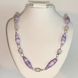 Necklace of soft purple stripes and lavender glitter with silver fixings on a white form with a beach background
