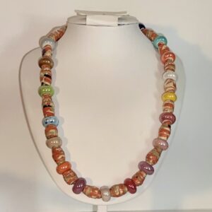 Orange bead necklace with glass beads as spacer beads on a white form with a neutral background