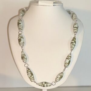 paper bead necklace with green and blue graphic design, with silver fixings on a white necklace form with a neutral background
