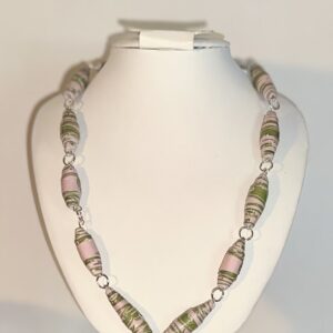 Pink and Green Graphic Design necklace withs silver fixings on a white necklace form with a neutral background