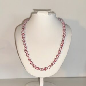 Necklace of mini red and white beads on a white necklace form in a neutral rbackground