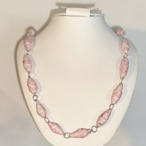 Pink and white textured pattern beads with silver fixings on a white necklace form with a neutral background