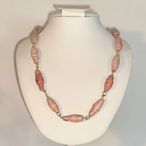 Necklace of pink variations paper beads necklace with gold fixings on a white form with a neutral background