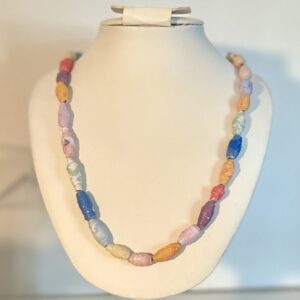 necklace of vibrant colored paper beads including some with flowers and glitter on a white form with a neutral background