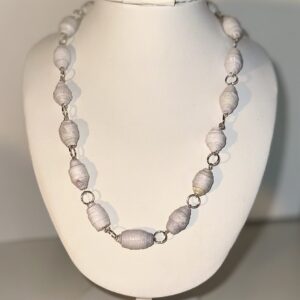 White paper-based beads connected with silver fixings into a necklace on a white form with a neutral background