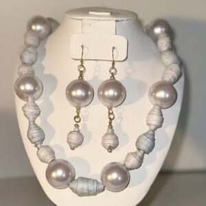 Necklace and earring set made of white leather-look paper beads and white glitter paper beads with gold fixings on a white display piece against a neutral background.