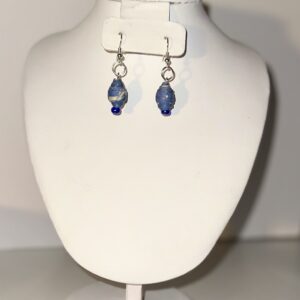 Denim blue dangle earrings with white spots, teardrop shape, silver fixings on a neutral background