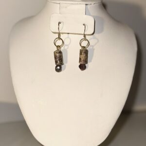 Dangle Earrings of Western look short cylinder paper beads with glass beads below with gold fixings on a neutral background