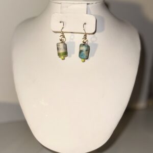 Earrings with gold fixings and small cylinders of green and blue on a neutral background
