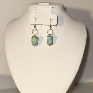 Mini Cylinders of blue and green with silver fixings on a wet sand each with a neutral background