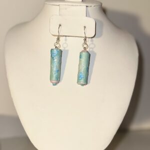 Earrings with silver fixings and long blue cylinders on a neutral background
