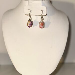 Hippie style paper-based bead earrings in a short cylinder style with gold fixings on a neutral background