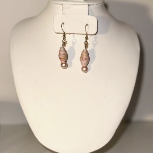 Gold fixings with pink fiesta design and colors with a pink pearl at the bottom on a neutral background