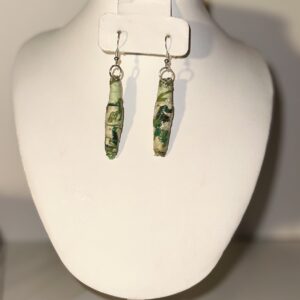 Long dangle earrings with a paper based white base decorated with green leaf-color variations withs silver fusing on a neutral background