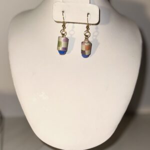 Earrings with gold fixings and multicolor checkered cylinder beads with blue glass beads below on a neutral background