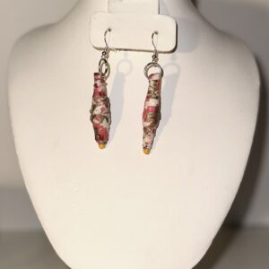Long dangle earrings with a white base and splatters of gold and pink/coral, with orange seed beads at the base and silver fixings on a neutral background